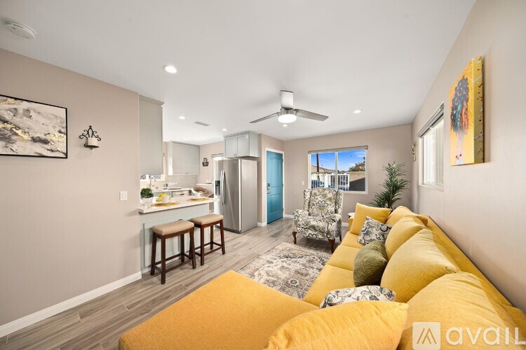 A living room with a yellow couch and a painting on the wall.
