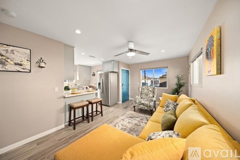 A living room with a yellow couch and a painting on the wall.