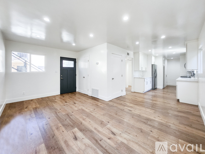 A spacious room with wooden flooring and white walls.