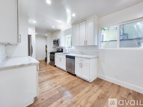 A kitchen with white cabinets and wooden floors is available for rent.