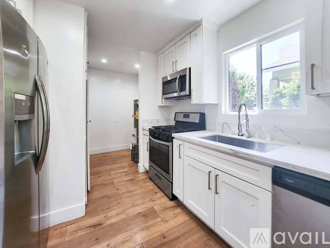 A kitchen with white cabinets and a wooden floor.