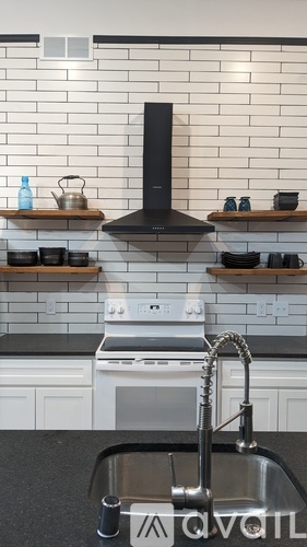 A kitchen with a black hood, white cabinets, and a stainless steel sink.