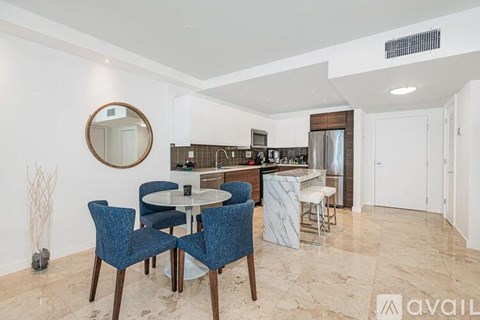 A dining area with a round table and blue chairs.
