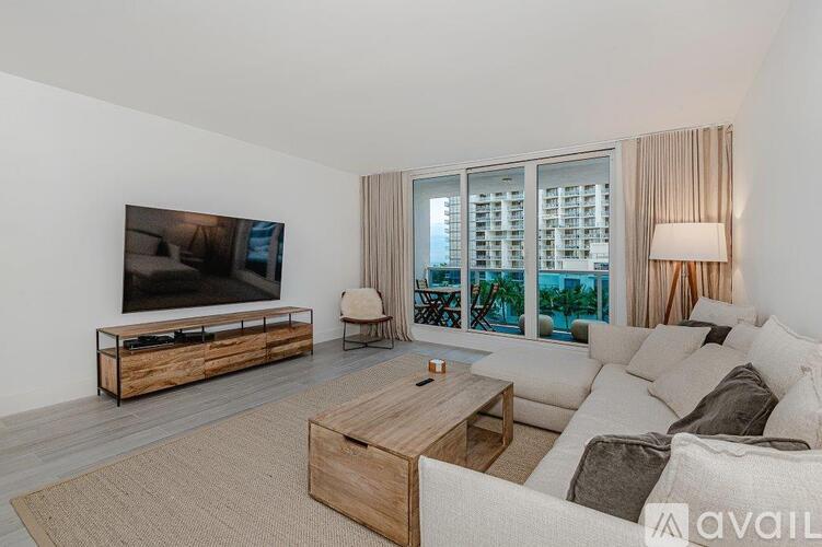 A modern living room with a flat screen TV and a large window overlooking a balcony.