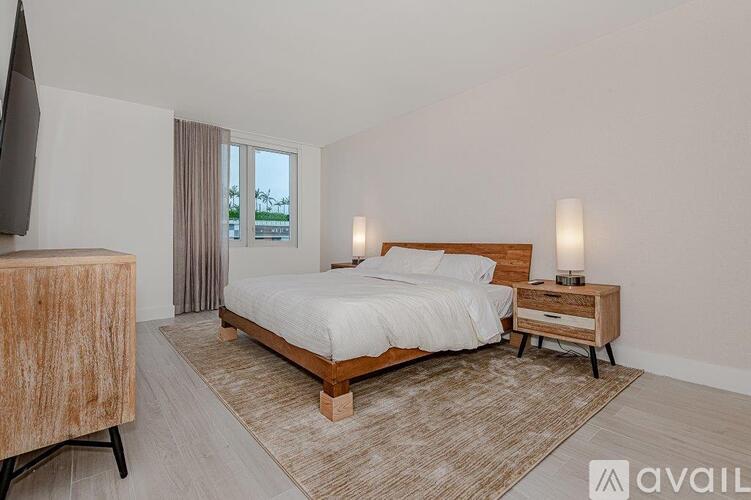 A bedroom with a large bed, a nightstand, and a television.