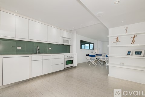 A modern kitchen with white cabinets and a green backsplash.