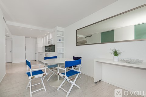 A white dining room with a round table and blue chairs.