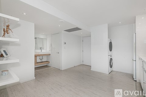 A spacious, white-walled room with a washing machine and a mirror.