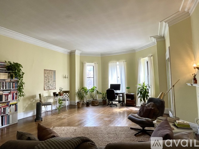 A living room with a large window, a couch, a chair, and a bookshelf.