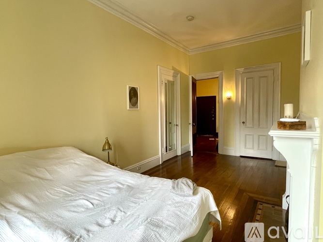 A bedroom with a bed, a fireplace, and a painting on the wall.