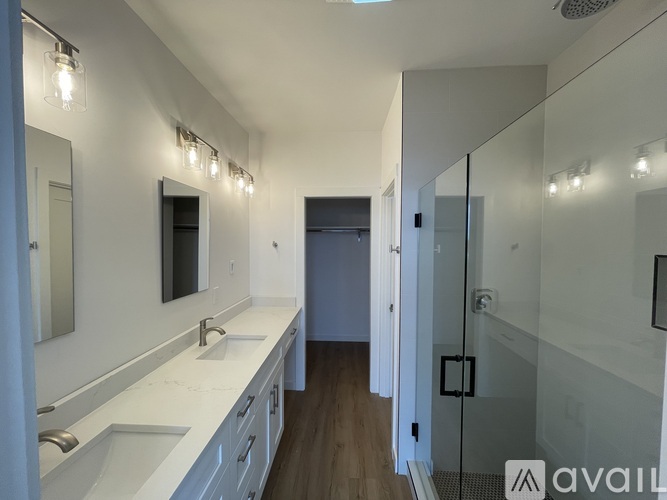 A bathroom with a white counter and a glass shower stall.