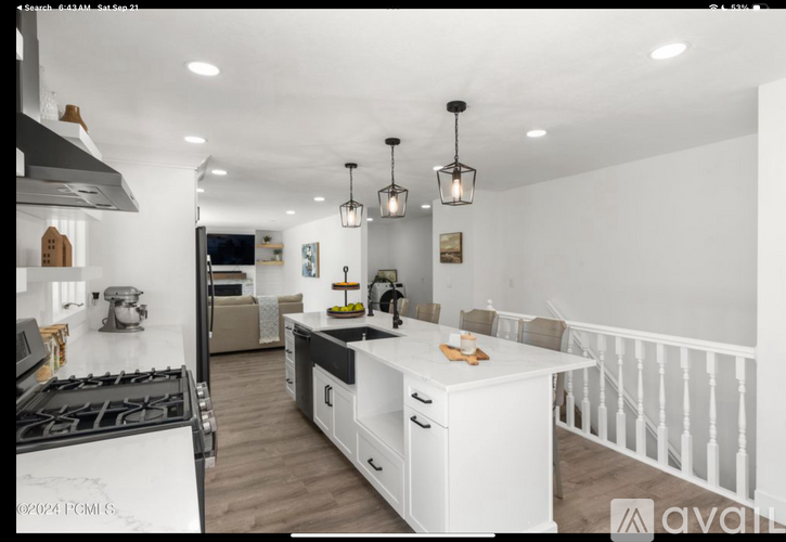 A modern kitchen with white cabinets and a wooden floor.