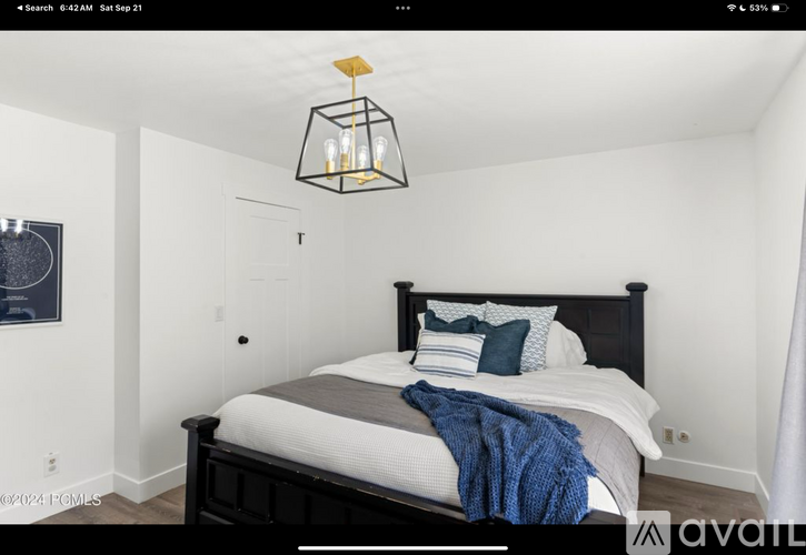 A bedroom with a bed, pillows, and a hanging light fixture.
