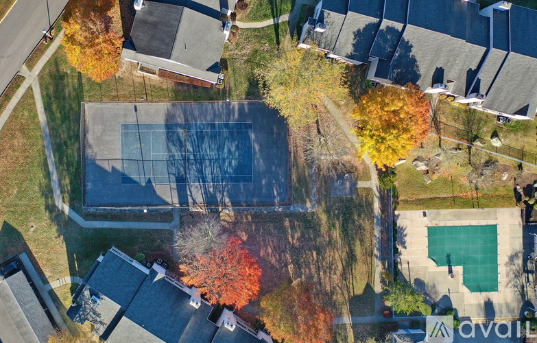 An aerial view of a tennis court surrounded by trees with autumn leaves.