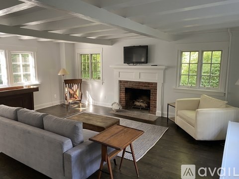 A living room with a grey couch, a wooden table, a fireplace, and a television.