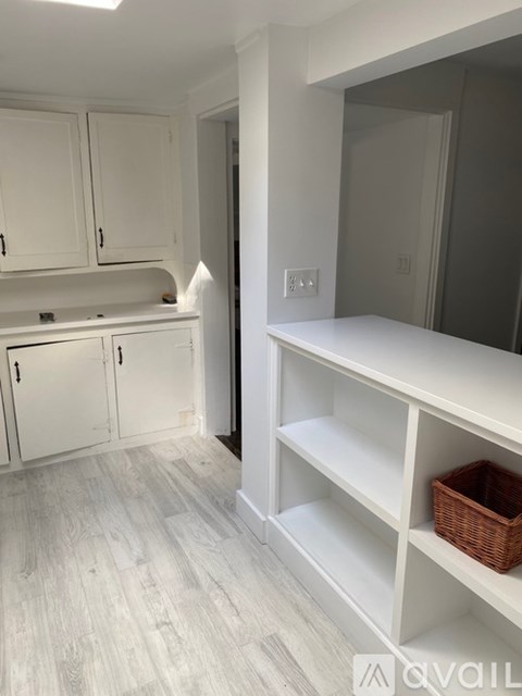 A kitchen with white cabinets and a white shelf.