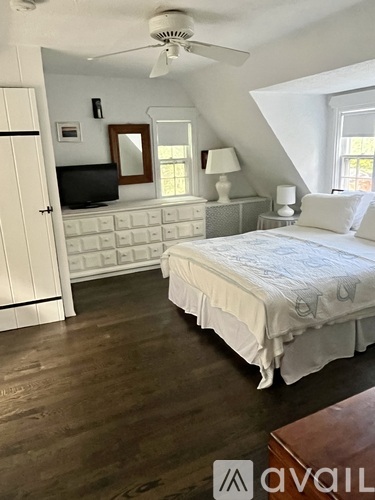A bedroom with a bed, dresser, and tv.