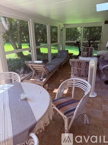 A patio with a table and chairs overlooking a grassy area.