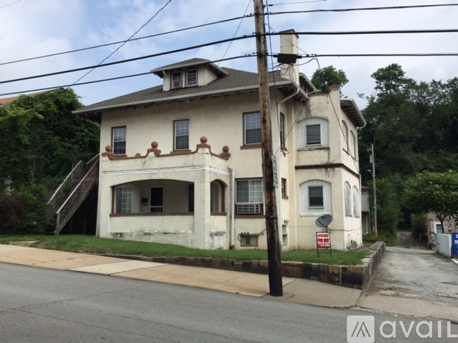A two-story house with a white facade and a brown roof.