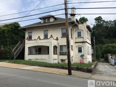 A two-story house with a white facade and a brown roof.
