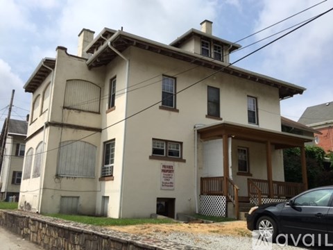 A house with a sign that says "For Sale" is in front of a car.