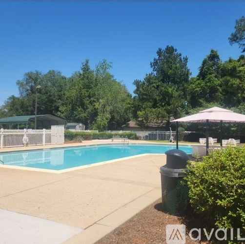 A pool surrounded by trees and a fence with a canopy.