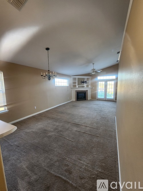A spacious room with a carpeted floor and a chandelier hanging from the ceiling.