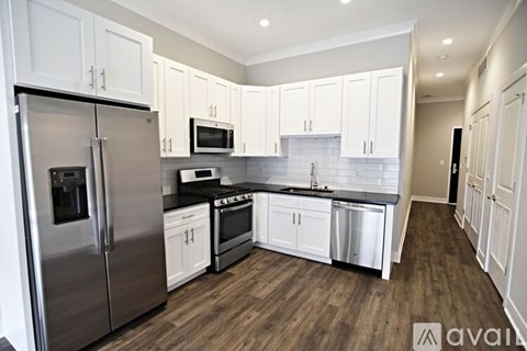 A kitchen with white cabinets and a stainless steel refrigerator.