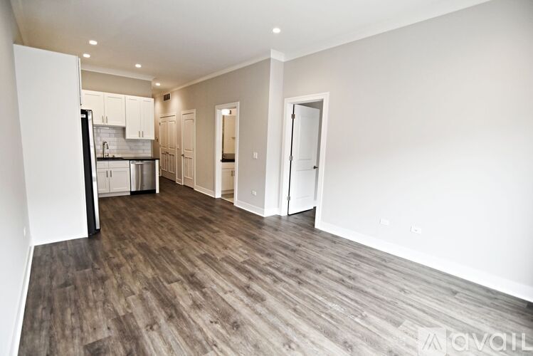 A spacious room with wooden flooring and white walls.