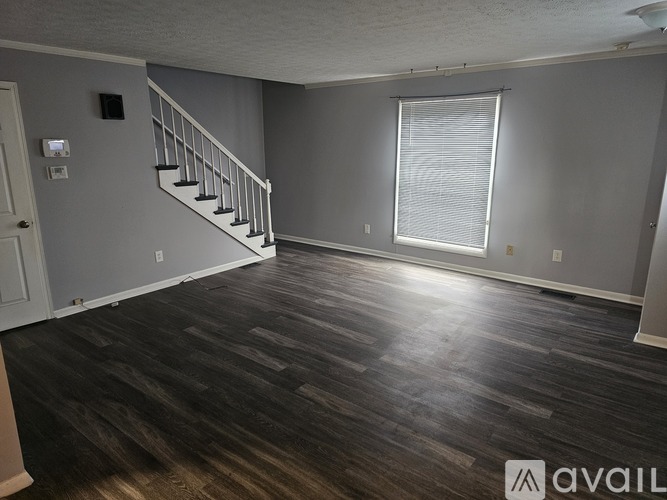 A room with wooden flooring and a staircase leading to the upper level.