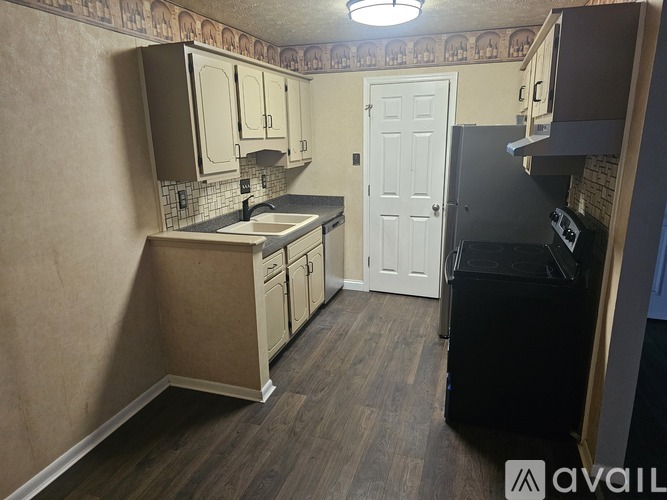 A kitchen with a black fridge, white cabinets, and a white door.