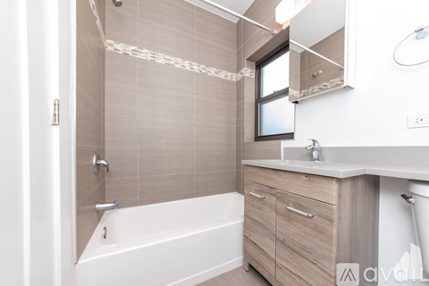 A bathroom with a white tub, sink, and a mirror above the sink.