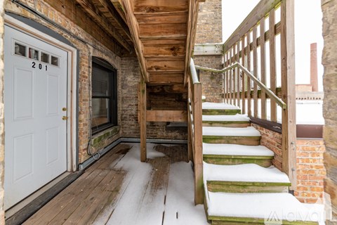 A wooden staircase with a white railing leads up to a door with the number 201 on it.