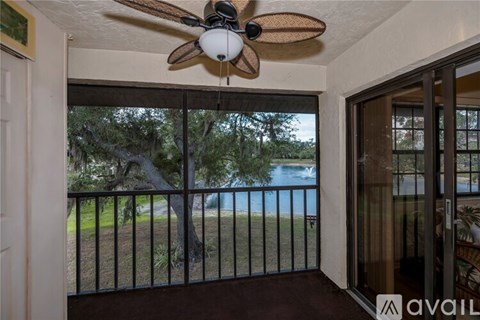 A room with a ceiling fan and a view of a pool through a sliding glass door.