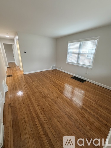 A room with wooden flooring and a window with blinds.