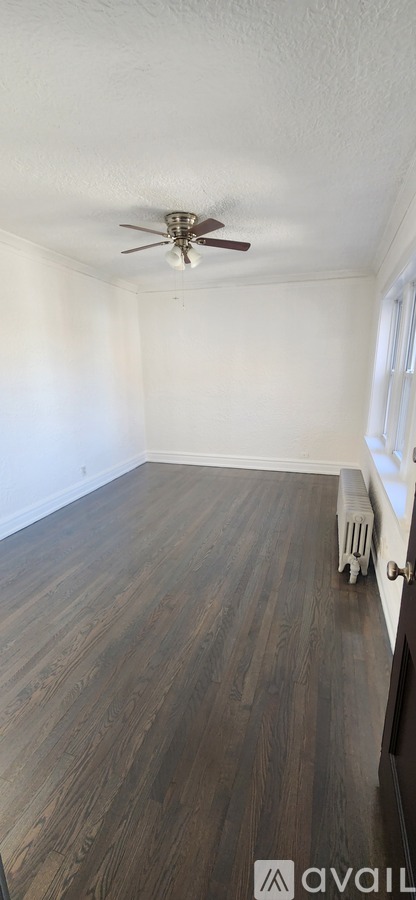 A room with a ceiling fan and wooden flooring.