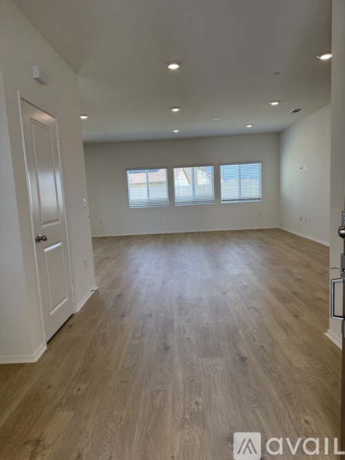 A spacious room with wooden flooring and white walls.