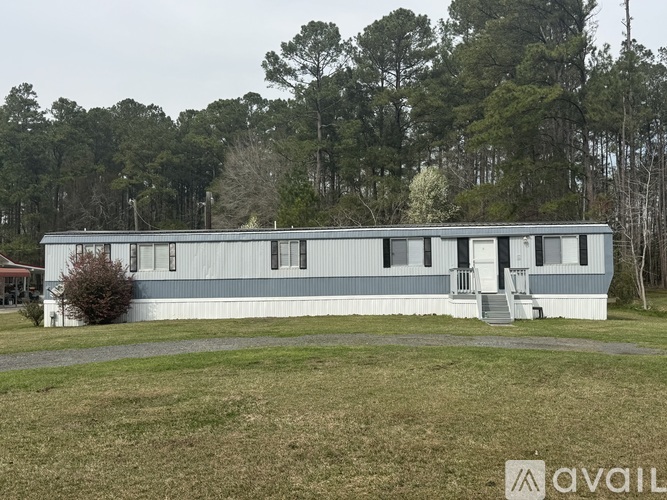 A blue building with a white door and windows is surrounded by trees.