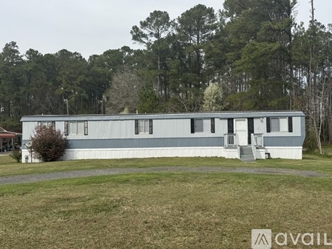 A blue building with a white door and windows is surrounded by trees.