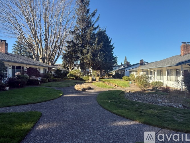 A gravel pathway leads through a grassy area between two houses.