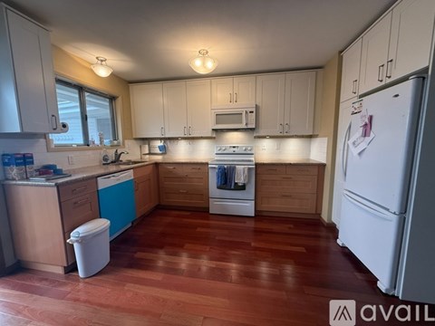 A kitchen with wooden floors and white appliances.