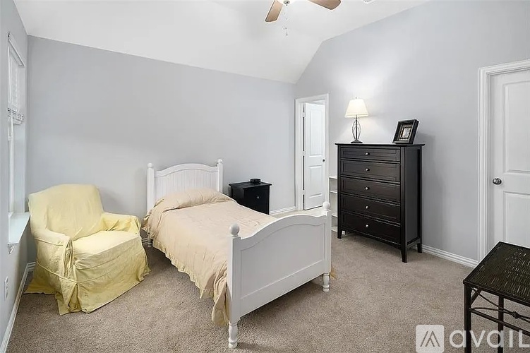 A bedroom with a bed, chair, and nightstand.