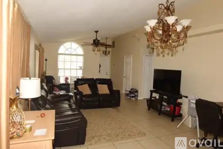 A living room with a chandelier, a television, and a couch.