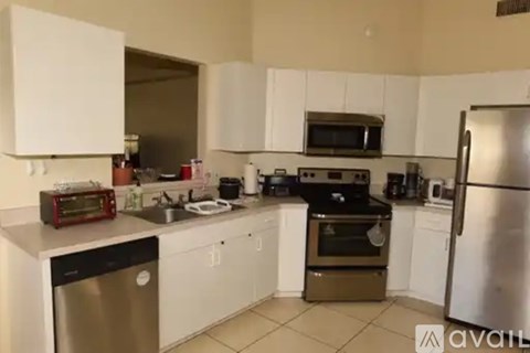 A kitchen with white cabinets and a stainless steel refrigerator.