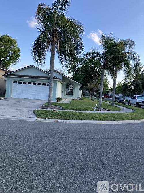 A house with a garage and palm trees in front.