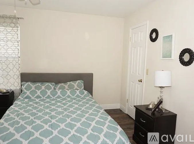 A bedroom with a bed, nightstand, and two wreaths on the wall.