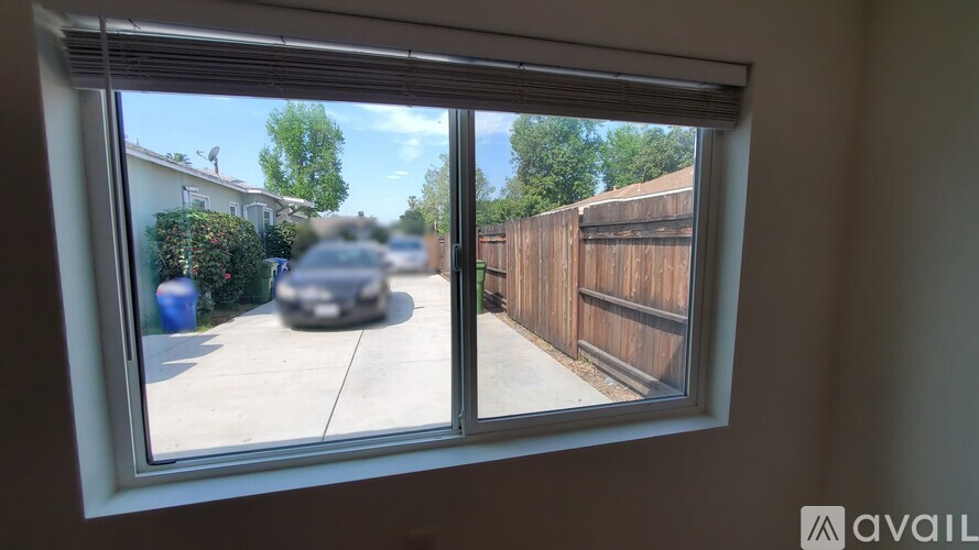 A window with a view of a car and a fence outside.