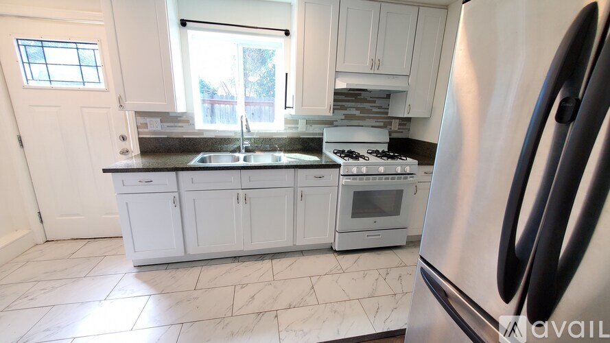A kitchen with white cabinets and a stainless steel refrigerator.