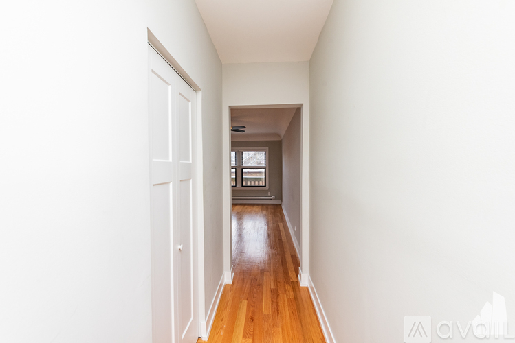 A long hallway with a door on the left and a window on the right.