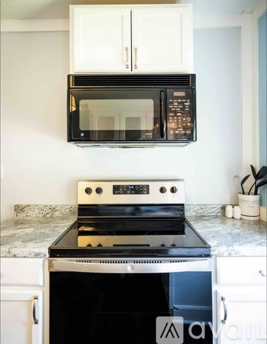 A black microwave oven is mounted above a stove with a white oven door.